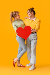 Fototapeta na wymiar Young transgender couple with red heart on color background. Valentine's Day celebration