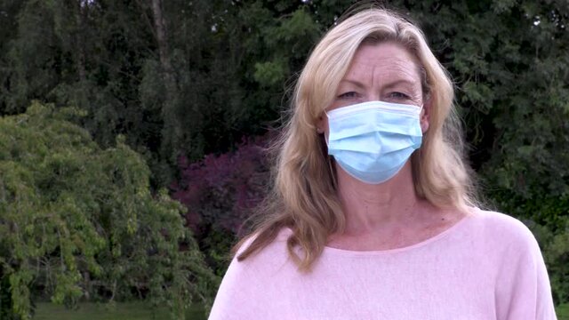 Middle aged blonde woman outside wearing a face mask during COVID-19 Coronavirus pandemic