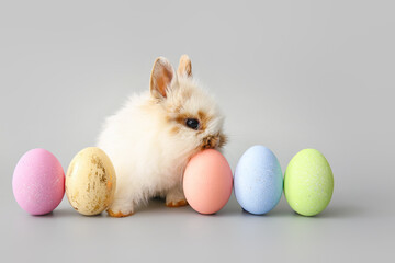 Cute rabbit and Easter eggs on grey background