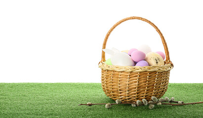 Fototapeta na wymiar Basket with Easter eggs on grass against white background