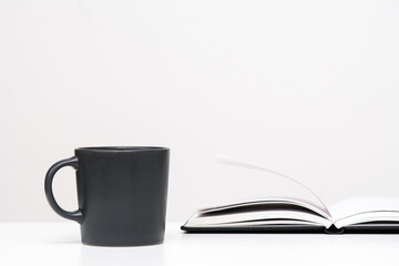 On a white background, a mug and an open diary. Concept - education and business.
