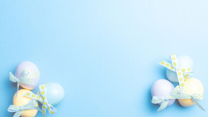 Easter eggs isolated. Colorful egg with tape ribbon on pastel blue background in Happy Easter decoration. Flat lay, top view.