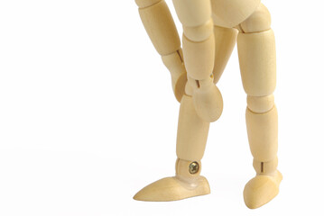 膝を押さえるポーズをした横向きの木製のモデル人形のアップ