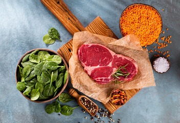 Fresh raw rib-eye steak on wooden cutting board.