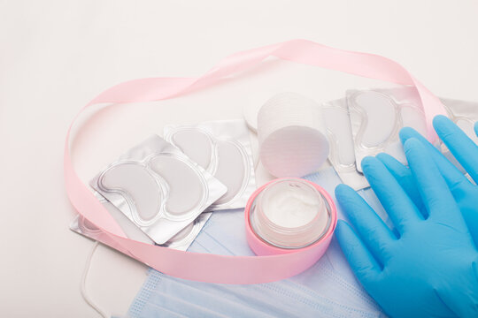Beauty accessories on white background. Blue gloves, masks, cream and patches.