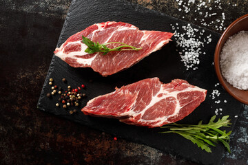 raw pork with spices for cooking on a fire or oven on a dark stone background