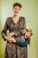 portrait of single mother and her pre-teen daughter against green background