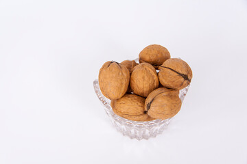 Walnuts in a shell on a white background in a crystal vase. Healthy nuts.