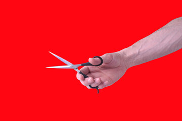 Male hand with scissors on red background