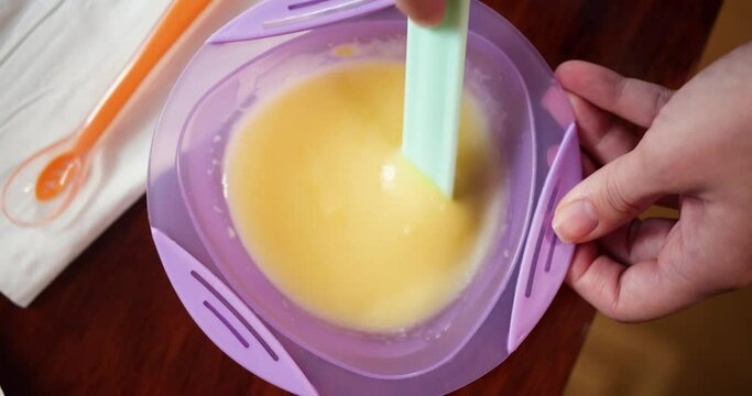 mother prepares baby porridge at home. slow motion