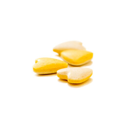 Heart shaped yellow vitamin pills on white background