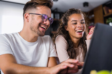 Beautiful interracial couple using laptop computer at home surfing the internet having good time