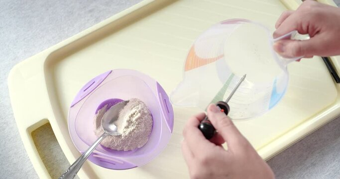 mother prepares baby porridge at home. slow motion