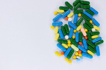 Pharmaceutical colorful pills and capsules on  white background.  A large number of tablets on the surface.
The concept of modern treatment, pharmacy, healthcare. Empty place for text. Top view. 