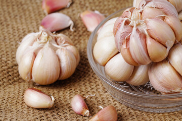 Garlic Cloves and Bulb in glass bowl on hemp sack.