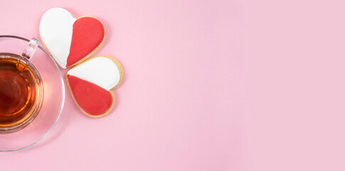 Red and white heart-shaped cookies next to a cup of tea