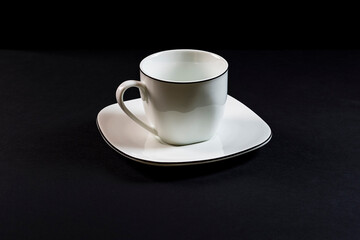 Porcelain cup and saucer on black background.Photography is a horizontal shot taken in a studio with artificial light.