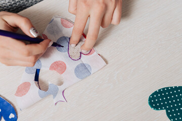 The girl draws a heart on the fabric using a stencil.