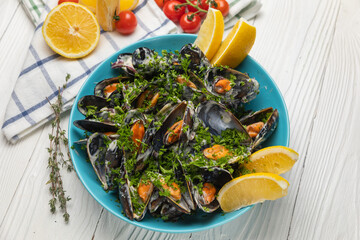 Mussels in a plate with lemon on a white table
