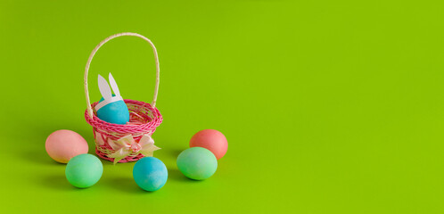 happy easter banner  decorated eggs in wicker basket on green background copy space