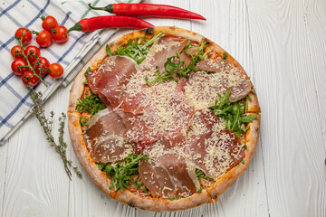 Pizza with prosciutto, arugula, tomatoes and parmesan
