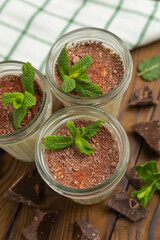 Tiramisu in a glass on a brown wooden table
