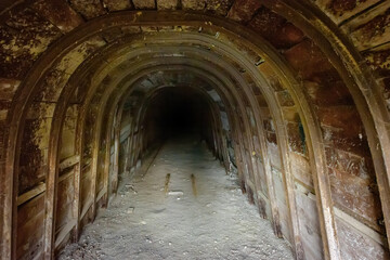 Fototapeta na wymiar Dark underground tunnel with wooden walls in abandoned mine 