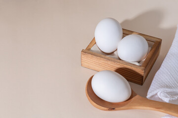 Chicken eggs in a wooden box on beige background with copy space, product with amino acids choline lecithin cholesterol calcium potassium phosphorus magnesium iodine protein vitamins healthy diet food