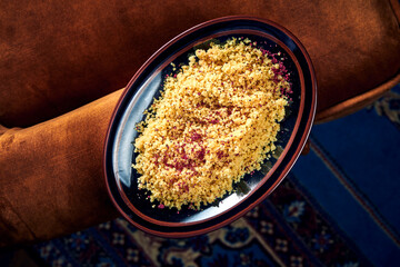 A tasty and healthy side dish for the main course - couscous porridge with oriental spices served in a black plate. Top view