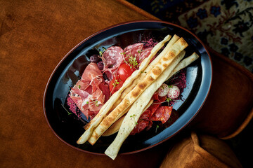Slicing Italian chorizos, salami, prosciutto di parma served in black plate. Restaurant food. Top...