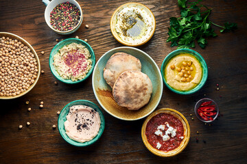 Meze is an oriental set of appetizers served in small bowls with pita on a wooden background....