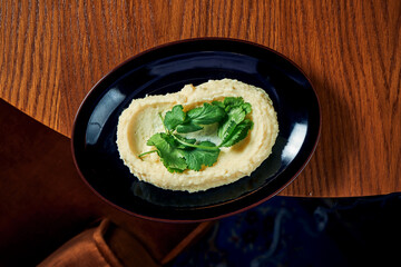 A classic side dish for main courses is mashed potatoes with cream and cilantro in a black plate. View from above