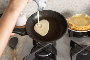 Person cooking thin pancakes on frying pan in kitchen. Cooking at home. close-up. selective focus