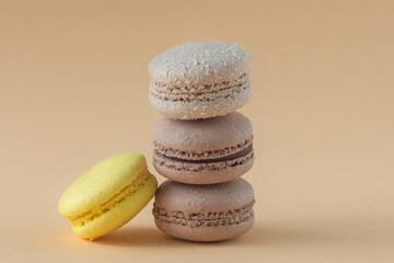 Fototapeta na wymiar chocolate macaroons are stacked on top of each other. Horizontal photo, beige background. Yellow French cookies.