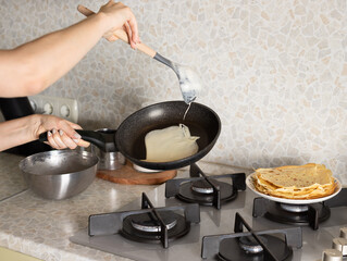 Woman preparing breakfast in kitchen at home. The process of preparing thin pancakes, crepes. Shrovetide, Maslenitsa holiday concept. selective focus