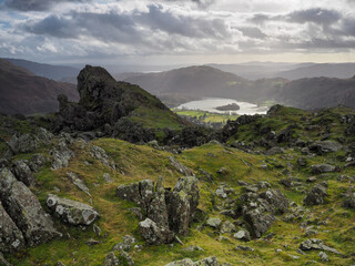 Fototapeta na wymiar Helm Crag and the rock formation known as the 'The Lion and the Lamb' with Grasmere in the background and a glimpse of Windermere and Coniston Water on the horizon, Lake District, UK