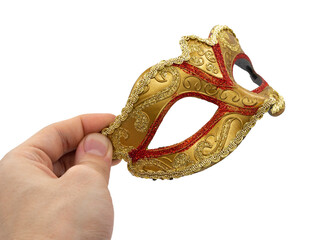 A man holds in his hand a traditional golden carnival Venetian mask with a red ornament on a black background. Preparation for the Brazilian Festival and Mardi Gras, fat Tuesday.