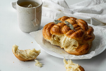 Freshly baked homemade braided brioche and cup of tea on white background.