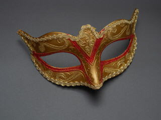 Traditional golden carnival Venetian mask with red ornament on a black background. Preparation for the Brazilian Festival and Mardi Gras.