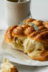 Freshly baked homemade braided brioche and cup of tea on white background.