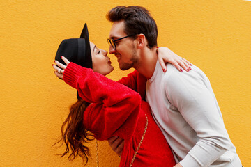 Adorable couple in love hugging and kissing on yellow background.