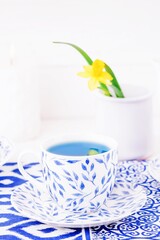 Cup with leaves pattern of organic blue tea and daffodil