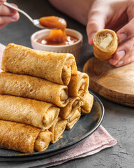 Thin crepe pancakes stuffed lie in a pyramid on the table in a rustic style. A traditional dish for the carnival.