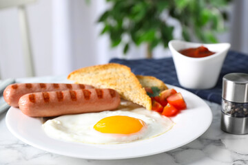 Tasty breakfast with fried egg and sausages served on white marble table indoors