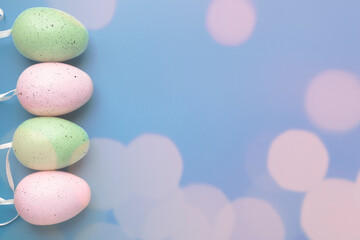 Easter background, eggs in pastel colors with bokeh and copy space on blue, egg hunt, happy party, spring holiday concept