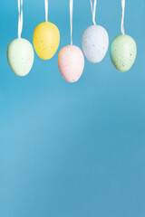 Easter background, Hanging eggs on blue, vertical banner with copy space