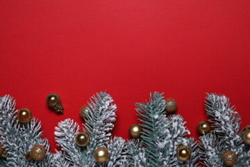 Christmas tree branches with golden baubles on red background, flat lay. Space for text