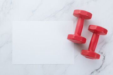 Blank white paper note and dumbells on white marble background. Sport flat lay, Healthy lifestyle and diet concept.