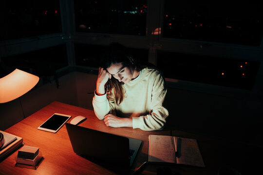 Caucasian Female Student Working Late At Night Tired Reading Articles For University On Laptop