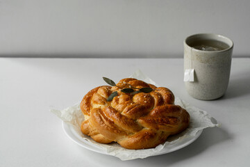 Freshly baked homemade braided brioche and cup of tea on white background.